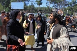 FILE - An Afghan woman protester (3L) speaks with a member (R) of the Taliban during a protest in Herat on Sept. 2, 2021.