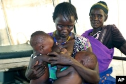 FILE - A mother breastfeeds her severely malnourished eight-month-old twins in a health clinic in Pibor, South Sudan, Dec. 16, 2020.