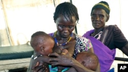 File - In this Wednesday Dec.16 2020 photo, Elizabeth Girosdh breastfeeds her eight-month old twins in a health clinic in Pibor, South Sudan as her children are severely malnourished and she sometimes doesn't have enough breastmilk to feed. 
