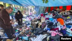 Para migran mencari pakaian di sebuah tenda darurat di luar kantor luar negeri di Brussels, Belgia (14/9). (Reuters/Yves Herman)