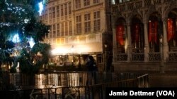 Một cặp đôi đang hôn nhau cạnh một cây Giáng Sinh thắp sáng nơi Quảng trường Grand, Brussels, Bỉ.