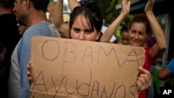 Una migrante cubana varada en Costa Rica muestra un cartel pidiendo ayuda al presidente de EE.UU. durante una protesta en noviembre de 2015. Países centroamericanos aprobaron un plan para ayudar a los migrantes a llegar a EE.UU. por vía aérea y terrestre.