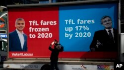 FILE - A cameraman films a campaign poster for the Labour Party candidate for mayor of London, Sadiq Khan, who became London's first Muslim mayor.