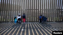 FILE - People hold conversations through the U.S. Mexico border wall at Border Field State Park in San Diego, California, Nov. 18, 2017. 