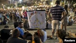 Left-wing protesters hold signs during a protest condemning Friday's arson attack in the West Bank, at Rabin square in Tel Aviv August 1, 2015.