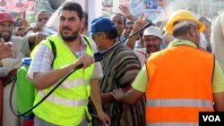 Men spray the hot crowds with cold water from plastic water packs and bottles. Currently fasting for the holy month of Ramadan, no one in this crowd takes a drink. (Heather Murdock for VOA)