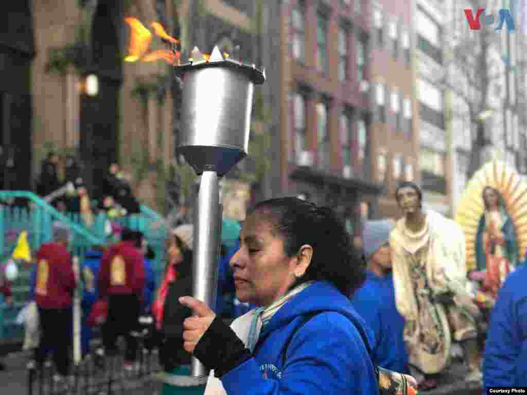 Una señora sostiene una torcha mientras camina en las calles de la Ciudad de Nueva York, rumbo a la Catedral de San Patricio.&nbsp; Foto: Celia Mendoza- VOA