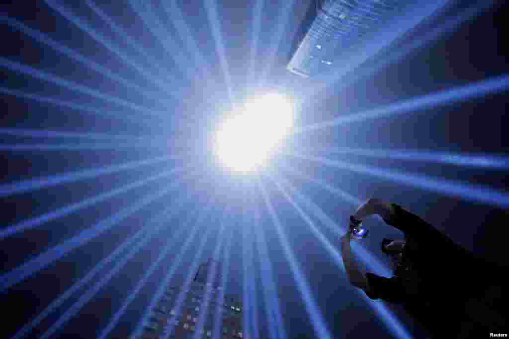 An EMT with the New York Fire Department and first responder Jason Butscher takes a photo of the Tribute In Light installation as it is illuminated over lower Manhattan to mark the 17th anniversary of the 9/11 attacks in New York City, Sept. 11, 2018.