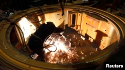 FILE - General Dynamics employees work on an Abrams battle tank during a tour of the Joint Systems Manufacturing Center, Lima Army Tank Plant, in Lima, Ohio.