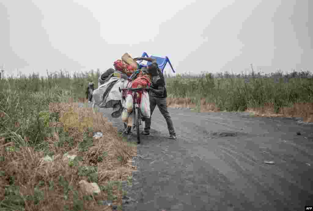 A man, one of the last to evacuate Nzulo, struggles as he pushes his belongings on the back of his bicycle as he leaves the area, near Nzulo, Democratic Republic of Congo.