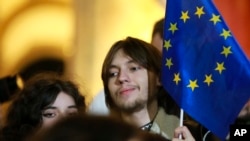 FILE - A young man holds an EU flag as he attends an opposition protest against the results of the parliamentary election in Tbilisi, Georgia, on Oct. 28, 2024.