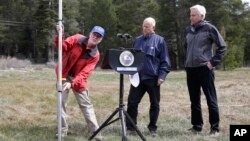 El gobernador de California, Jerry Brown (centro) observa hasta donde debería estar la nieve en las montañas de la Sierra Nevada.