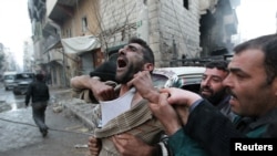 FILE - A father reacts after the death of two of his children, whom activists said were killed by shelling by forces loyal to Syria's President Bashar al-Assad, at al-Ansari area in Aleppo, Jan. 3, 2013. 