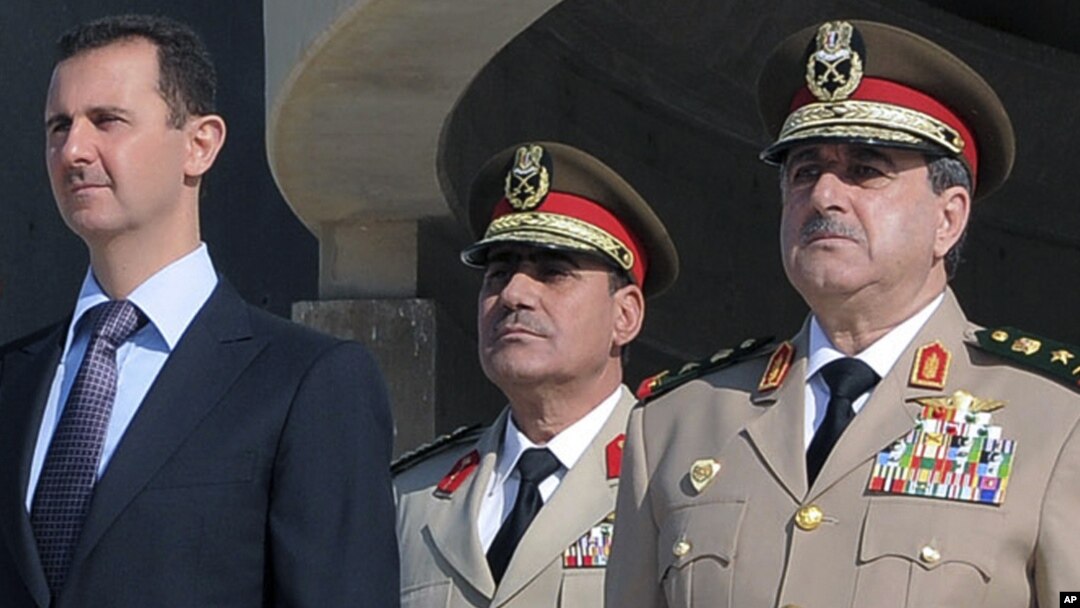 Chapdan prezident Bashar al-Assad, kimligi noma'lum harbiy va o'ngda, bugungi portlashda halok bo'lgan Mudofaa vaziri Dovud Rajha 