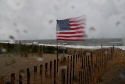 Una bandera estadounidense sopla con fuertes vientos en la playa, se esperaba que la tormenta tropical Fay se extendiera por el noreste de Estados Unidos, en la sección Rockaways del distrito de Queens de Nueva York.