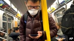 FILE - In this March 12, 2020, photo, a commuter wears a mask while riding the subway in New York.