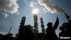 FILE - A worker at the Valero St. Charles Oil Refiner is seen in silhouette in Norco, Louisiana.