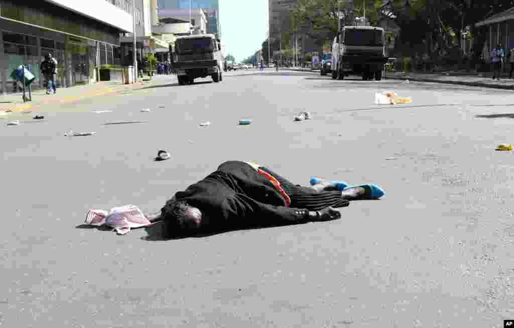 A woman lies in the road after been injured by police during protests in Harare.