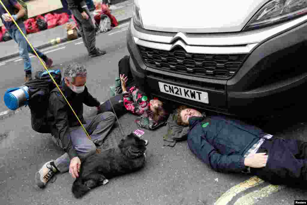 People tie themselves to a vehicle during a protest of Extinction Rebellion climate activists, in central London, Britain.