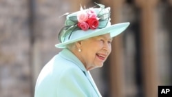 FILE - Britain's Queen Elizabeth smiles after awarding Captain Sir Thomas Moore his knighthood during a ceremony at Windsor Castle in Windsor, England, July 17, 2020.