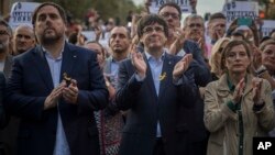 Para pemimpin Catalonia, dari kiri: Wakil Presiden Oriol Junqueras, Presiden Carles Puigdemont, Ketua parlemen regional Catalan Carme Forcadell, bertepuk tangan dalam aksi protes di Barcelona, Sabtu (21/10). 