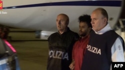 This handout picture released by the Italian police (Polizia di Stato), on June 8, 2016 shows Medhanie Yehdego Mered, 35, an Eritrean suspected of controlling a migrant trafficking network, escorted by policemen upon his extradition from Sudan to Italy late on June 6, 2016.