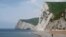 FILE - A man takes photographs pointing south on the beach at Durdle Door with the English Channel sea connecting Britain to mainland Europe seen behind, in southwest England, May 13, 2016. 