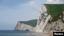 FILE - A man takes photographs pointing south on the beach at Durdle Door with the English Channel sea connecting Britain to mainland Europe seen behind, in south west England, May 13, 2016. 