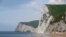 FILE - A man takes photographs pointing south on the beach at Durdle Door with the English Channel sea connecting Britain to mainland Europe seen behind, in south west England, May 13, 2016. 