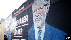 A man adds the finishing touch to a newly painted mural of Gerry Adams on the Falls Road, West Belfast, Northern Ireland, May, 2 2014.