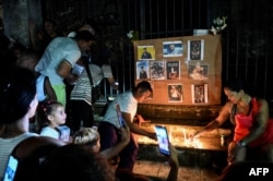 Los cubanos, de todas las edades ponen ofrendas junto a fotografías del fallecido cantante de reggaetón José Manuel Carbajal. "El Taiger", durante un homenaje en La Habana el 10 de octubre de 2024.