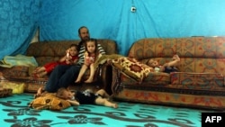 A Syrian refugee from Aleppo sits with his children in a makeshift tent in a Syrian refugee camp in the town of Kab Elias in Lebanon's Bekaa Valley, June 20, 2016.