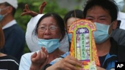 Families of victims of a train crash cry as they try to conjure their spirits near Taroko Gorge in Hualien, Taiwan, April 3, 2021. The train partly derailed in eastern Taiwan on Friday after colliding with an unmanned vehicle that had rolled down a hill.