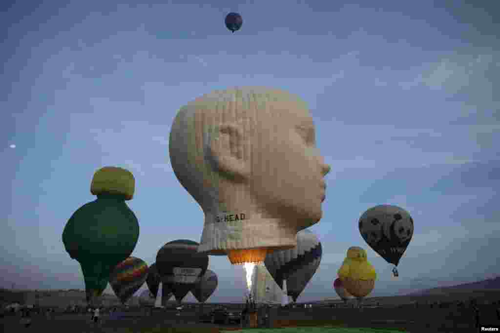 Hot air balloons are prepared for a flight as others take off during an international hot air balloon festival at Maayan Harod National park in northern Israel.