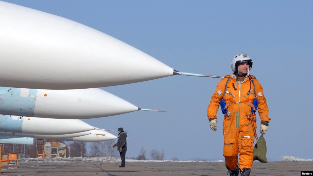 Seorang pilot berjalan melewati jet tempur SU-27SM di pangkalan udara militer di kota timur jauh Rusia, Vladivostok. Rusia mengerahkan dua pesawat bomber jarak jauh berkapasitas nuklir untuk berpatroli di atas wilayah Belarus barat. (Foto: Reuters)