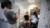 A woman takes a picture of a man as he receives a third shot of the COVID-19 vaccine as the country launches booster shots for people over 40 years old, in Jerusalem, August 20, 2021. 