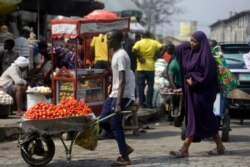 FILE - In this Dec. 24, 2020, file photo, people walk in a market in Lagos, Nigeria. A survey of people aged 18-24 in 15 countries has found that many Africans are battling the economic downturns caused by the COVID-19 pandemic.