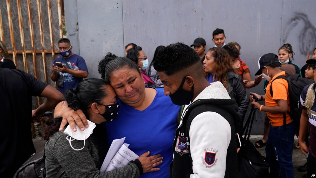 Lizeth Morales de Honduras y su hijo Alex Cortillo, reciben un abrazo de Erika Valladares Ponce, mientras esperan cruzar a Estados Unidos para comenzar el proceso de asilo el lunes 5 de julio de 2021 en Tijuana, México.