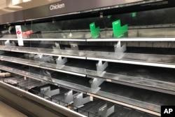FILE - Shelves that usually hold an abundance of chicken and beef lay empty at a Target in Abington, Pennsylvania., March 18, 2020.