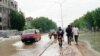 Les piétons marchent sur un trottoir boueux tandis que les véhicules pataugent dans une rue inondée par des pluies diluviennes à N'Djamena, au Tchad, le 19 août 2020. (Photo: André Kodmadjingar/VOA)