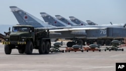 FILE - In this June 18, 2016, photo, Russian fighter jets and bombers are parked at Hemeimeem air base in Syria. 