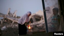 A Palestinian woman makes coffee on a fire outside her makeshift shelter near the ruins of her house, which witnesses said was destroyed during the Israeli offensive, in Al Mughraga village, south of Gaza City, Sept. 8, 2014. 