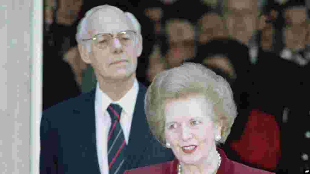 Margaret Thatcher a falar aos jornalistas enquanto o marido Dennis Thatcher escuta no momento em que diexava a&nbsp; 10 Downing Street, Westminster para o Pal&aacute;cio de Buckingham onde ia apresentar a sua demiss&atilde;o de primeira-ministra.&nbsp; (28 Novembro 1990.