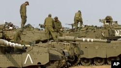 Israeli soldiers work on their a tanks in a staging ground in southern Israel, near the border with Gaza Strip, November 17, 2012. 