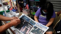 FILE - A man buys a newspaper at a makeshift stand after Joe Biden was projected the winner of the 2020 U.S. presidential election, in Manila, Philippines, Nov. 9, 2020. 
