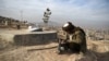 FILE - A man reads the Quran besides his relative's grave in a cemetery on the outskirts of Kabul, Afghanistan, Jan. 14, 2021.