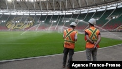 FILE - Workers from the Magil company standing near the pitch at the Olembe stadium in Yaounde, Cameroon, Aug. 8, 2021.