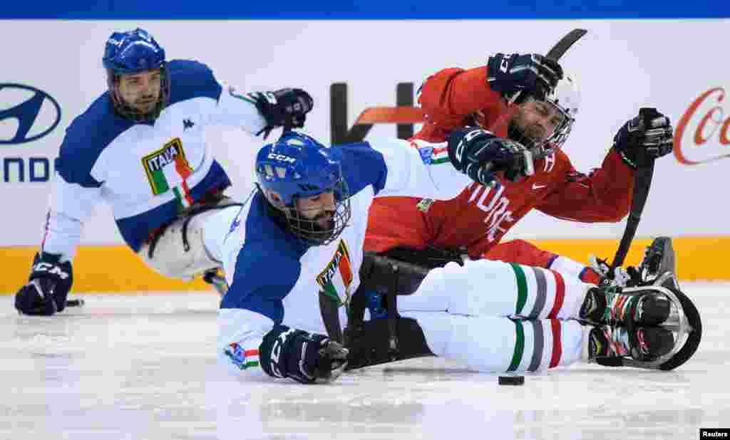 Andrea Macri dari Italia dan Morten Vaernes dari Norwegia memperebutkan cakram hoki es (puck) dalam pertandingan awal Grup A Hoki Es antara Norwegia dan Italia di Gangneung Hockey Centre di Paralimpiade Musim Dingin, PyeongChang, Korea Selatan, 19 Maret 2018.