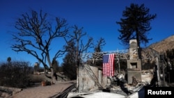 Bendera AS tergantung di rumah rusak saat kebakaran Eaton melanda Altadena, California, 14 Januari 2025. (Foto: Shannon Stapleton/Reuters)