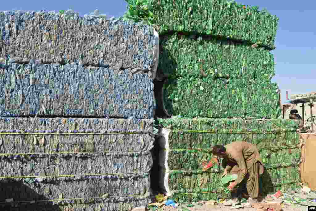 A laborer works next to the pile of used plastic bottles at a recycling factory in Quetta, Pakistan.